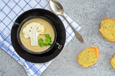 Taze yapılmış ev yapımı karnabahar çorbası maydanoz ve tost beyaz ekmek ile ot tereyağı yayılmış bir mutfak yüzeyi-sağlıklı ve vejetaryen öğle yemeği ile karnabahar ve krem