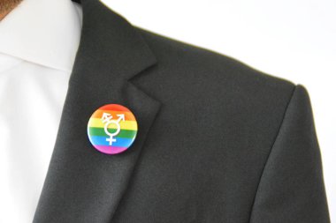 20'li yaşlarının ortasında bir adam takım ceketinde transseksüel sembolü olan bir düğme takıyor - Çalışma Hayatında Kabul ve Hoşgörü Kavramı