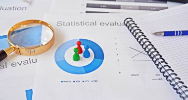 Genç bir adam, istatistik rakamları bakarak, elinde bir büyüteç tutuyor-örnekleme ve doğru hedef grubu seçerek ve onu inceleyerek konu üzerinde bir iş kavramı 