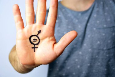 Onun orta yirmili bir adam elinde cinsiyet eşitliği bir işareti boyalı ve kamera gösterir-erkek ve kadınlar arasında eşitlik talep için bir kavram 