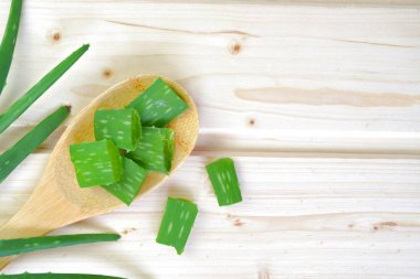 Bir Aloe Vera bitki ahşap bir pişirme kaşığı küçük şeritler halinde kesilir. Bu açık ahşap bir yüzeyde yatıyor. Yeşil Aloe Vera ve açık ahşap ile güçlü kontrast 