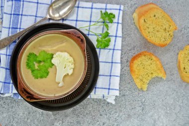 Taze yapılmış ev yapımı karnabahar çorbası maydanoz ve tost beyaz ekmek ile ot tereyağı yayılmış bir mutfak yüzeyi-sağlıklı ve vejetaryen öğle yemeği ile karnabahar ve krem