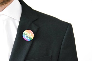 20'li yaşlarının ortasında bir adam takım ceketinde transseksüel sembolü olan bir düğme takıyor - Çalışma Hayatında Kabul ve Hoşgörü Kavramı