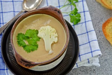 Taze yapılmış ev yapımı karnabahar çorbası maydanoz ve tost beyaz ekmek ile ot tereyağı yayılmış bir mutfak yüzeyi-sağlıklı ve vejetaryen öğle yemeği ile karnabahar ve krem