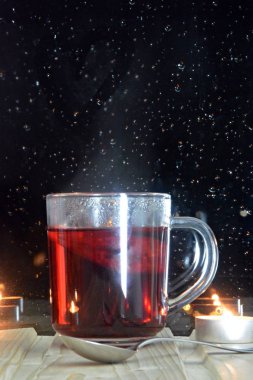 Gece ışıkları görülebilir bir yağmur ıslatılmış pencerenin önünde gece ahşap pencere üzerinde duran meyve çayı büyük bir bardak-çay bir fincan rahat yağmurlu gece 