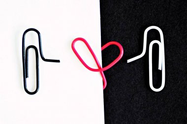 Beyaz kırpılmış ataş siyah bir yüzeyde oturur ve başka bir siyah ataç beyaz bir katta oturur, kırmızı bir ataç arasında bir kalp içine bükülmüş ile-ataç ile aşk kavramı 