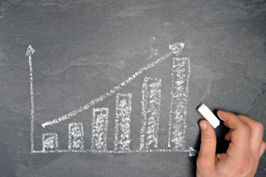 Ekonomik bağlamda istatistik ve değerlendirmeler için tebeşir konsepti ile çizilmiş siyah mermer yüzeyde bir ayaklanma şeması 