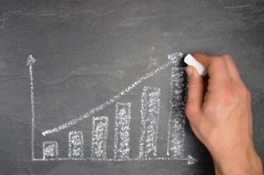 Ekonomik bağlamda istatistik ve değerlendirmeler için tebeşir konsepti ile çizilmiş siyah mermer yüzeyde bir ayaklanma şeması 