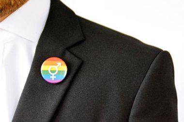 20'li yaşlarının ortasında bir adam takım ceketinde transseksüel sembolü olan bir düğme takıyor - Çalışma Hayatında Kabul ve Hoşgörü Kavramı