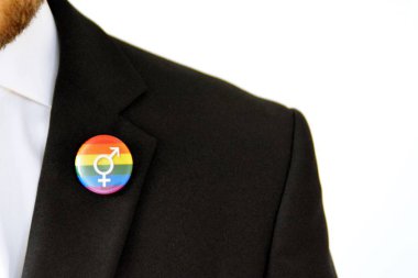 20'li yaşlarının ortasında bir adam takım ceketinde transseksüel sembolü olan bir düğme takıyor - Çalışma Hayatında Kabul ve Hoşgörü Kavramı