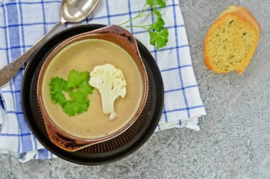 Taze yapılmış ev yapımı karnabahar çorbası maydanoz ve tost beyaz ekmek ile ot tereyağı yayılmış bir mutfak yüzeyi-sağlıklı ve vejetaryen öğle yemeği ile karnabahar ve krem