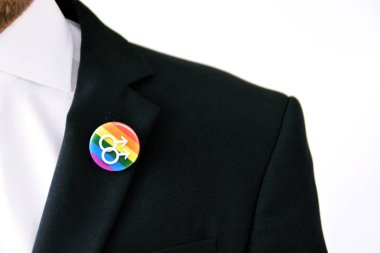 20'li yaşlarının ortasında bir adam takım ceketinde transseksüel sembolü olan bir düğme takıyor - Çalışma Hayatında Kabul ve Hoşgörü Kavramı