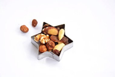 Bir yıldız şeklinde bir çerez kesici beyaz bir arka planda yatıyor ve metin veya nesneler için yer ile Noel şekilleri yumurta kabuğu zengin fındık ile farklı fındık ve kuru üzüm-kavramı ile doldurulur