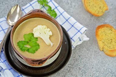 Taze yapılmış ev yapımı karnabahar çorbası maydanoz ve tost beyaz ekmek ile ot tereyağı yayılmış bir mutfak yüzeyi-sağlıklı ve vejetaryen öğle yemeği ile karnabahar ve krem