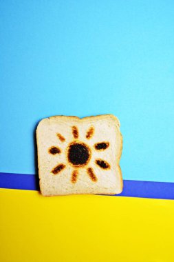 Bir tost renkli bir arka planda yatıyor, tost tamamen kızarmış değil, sadece bir güneşin kontur görünür-güneş yanığı kavramı tost yanıkları ile gösterilen