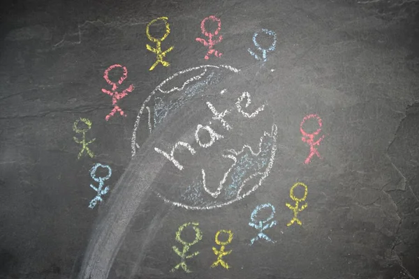 On a dark stone surface, a globe was painted with chalk and different-colored male figures drawn on the outside - concept of diversity and tolerance represented worldwide by a chalk drawing