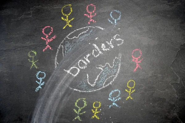 On a dark stone surface, a globe was painted with chalk and different-colored male figures drawn on the outside - concept of diversity and tolerance represented worldwide by a chalk drawing