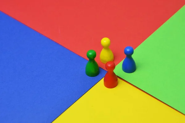 Different colored little men stand on the same colored surface - concept with game figures, colors and a meeting of these to represent the diversity of a team -