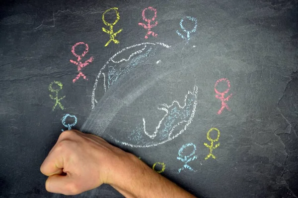 On a dark stone surface, a globe was painted with chalk and different-colored male figures drawn on the outside - concept of diversity and tolerance represented worldwide by a chalk drawing