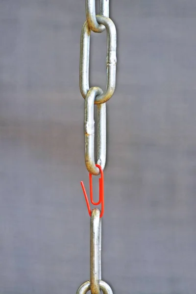 Ένας Κόκκινος Συνδετήρας Κρατά Δύο Αλυσίδες Χάλυβα Τελειώνει Μαζί Ασθενέστερο — Φωτογραφία Αρχείου