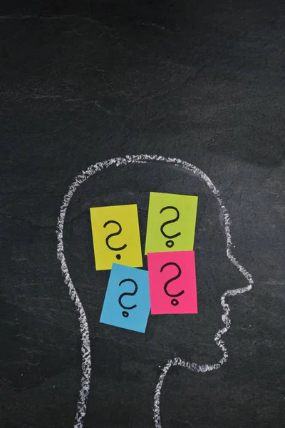 The silhouette of a head drawn with chalk on a dark stone surface as a concept and symbol for the thought process and the brainstorming for the unfolding of creativity and problem solving