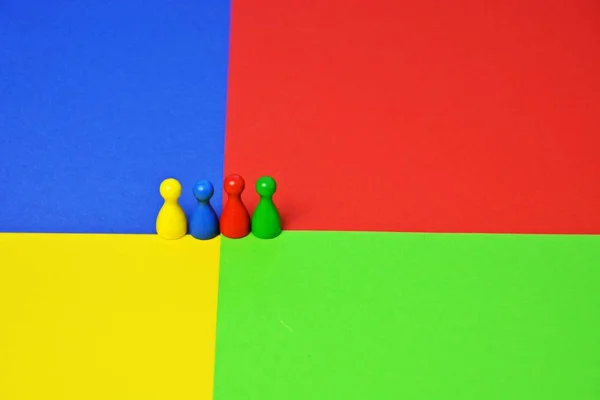 Different colored little men stand on the same colored surface - concept with game figures, colors and a meeting of these to represent the diversity of a team