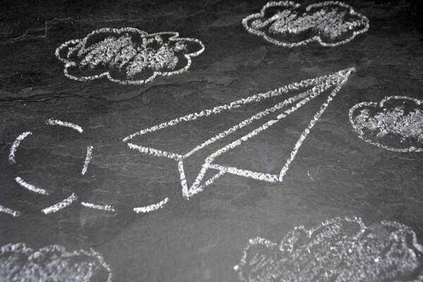 Мелом нарисован бумажный самолет и меткий путь на темной мраморной поверхности - фон с летающим бумажным самолетом
