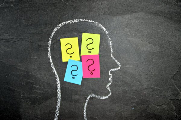 The silhouette of a head drawn with chalk on a dark stone surface as a concept and symbol for the thought process and the brainstorming for the unfolding of creativity and problem solving