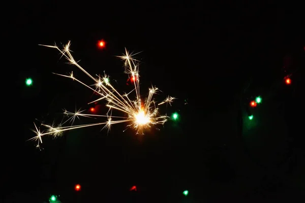 色付きのライトの前の夜のスパークラー 大晦日に スパークラーはゆっくりと燃え尽き すべての方向に火花を散らします — ストック写真