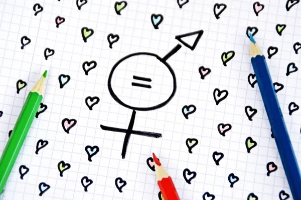 A sign for the equality of man and woman consisting of the respective gender signs and a match with painted hearts and colored pencils on a drawn sheet -equality man and woman symbolically represented