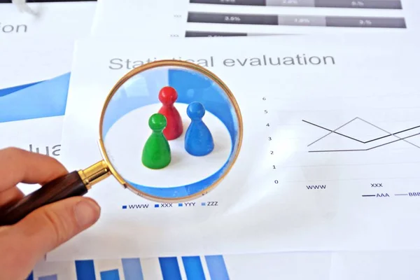 Genç bir adam, istatistik rakamları bakarak, elinde bir büyüteç tutuyor-örnekleme ve doğru hedef grubu seçerek ve onu inceleyerek konu üzerinde bir iş kavramı 