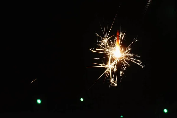 色付きのライトの前の夜のスパークラー 大晦日に スパークラーはゆっくりと燃え尽き すべての方向に火花を散らします — ストック写真