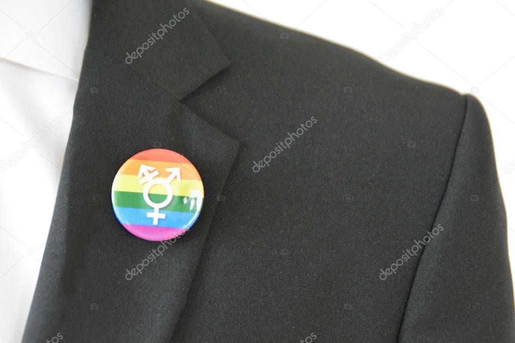 A man in his mid-twenties wears a button with the symbol for transgender on his suit jacket - Concept for Acceptance and Tolerance in Working Life