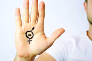 Onun orta yirmili bir adam elinde cinsiyet eşitliği bir işareti boyalı ve kamera gösterir-erkek ve kadınlar arasında eşitlik talep için bir kavram 