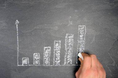 Ekonomik bağlamda istatistik ve değerlendirmeler için tebeşir konsepti ile çizilmiş siyah mermer yüzeyde bir ayaklanma şeması 