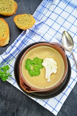 Taze yapılmış ev yapımı karnabahar çorbası maydanoz ve tost beyaz ekmek ile ot tereyağı yayılmış bir mutfak yüzeyi-sağlıklı ve vejetaryen öğle yemeği ile karnabahar ve krem