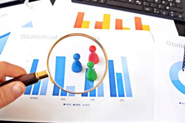 Genç bir adam, istatistik rakamları bakarak, elinde bir büyüteç tutuyor-örnekleme ve doğru hedef grubu seçerek ve onu inceleyerek konu üzerinde bir iş kavramı 