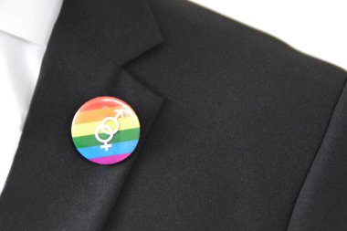 20'li yaşlarının ortasında bir adam takım ceketinde transseksüel sembolü olan bir düğme takıyor - Çalışma Hayatında Kabul ve Hoşgörü Kavramı