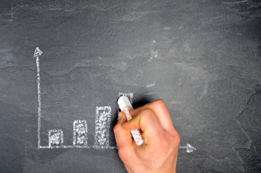 Ekonomik bağlamda istatistik ve değerlendirmeler için tebeşir konsepti ile çizilmiş siyah mermer yüzeyde bir ayaklanma şeması 