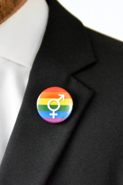 20'li yaşlarının ortasında bir adam takım ceketinde transseksüel sembolü olan bir düğme takıyor - Çalışma Hayatında Kabul ve Hoşgörü Kavramı