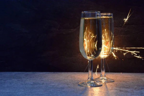 Twee Gevulde Champagne Fluiten Staan Het Donker Voor Een Sparkler — Stockfoto