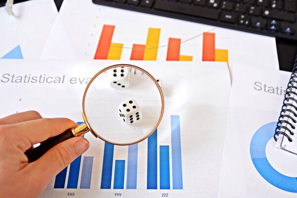A young man holding dice in the hand and in the background are statistical evaluations to see - concept that represents the decision making as a cube in whicha random recommendation is made 