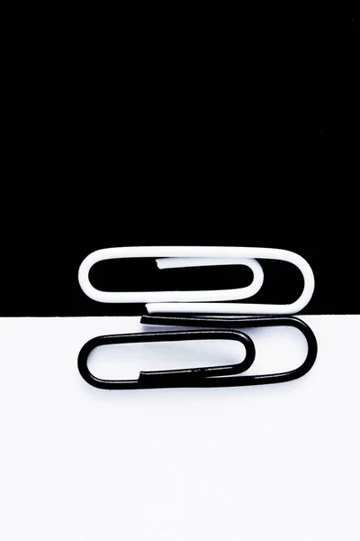 Een White Clip Paperclip Zit Een Zwart Oppervlak Een Andere — Stockfoto