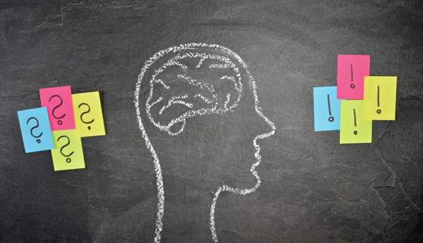 The silhouette of a head drawn with chalk on a dark stone surface as a concept and symbol for the thought process and the brainstorming for the unfolding of creativity and problem solving