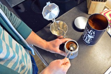 20'li yaşlarda bir adam espresso makinesiyle kahve hazırlar. 