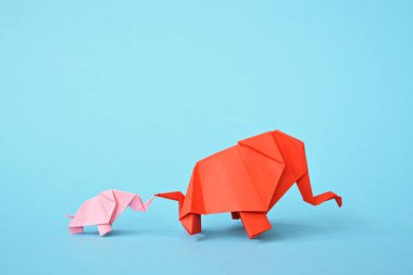 Mavi bir arka plan üzerinde pembe ve kırmızı stand iki kağıt katlanmış filler - küçük bir bebek fil ve origami tekniğine göre katlanmış bir anne fil ile kavram