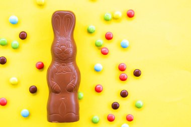 Bir Paskalya tavşanı dışında renkli çikolata parçaları ile çikolata yapılmış tek amaçlı bir yüzey üzerinde yatıyor - renkli bir yüzeyüzerinde tatlılar paskalya