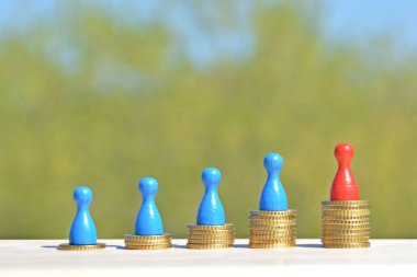  sikke farklı yüksekliklerde yığılmış, yükselen bir kulak sonuçlanan. Her yığını üzerinde evler ve bir oyun figürü finansmanı sembolize bir ev standları-metin için oda ile