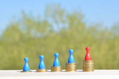  sikke farklı yüksekliklerde yığılmış, yükselen bir kulak sonuçlanan. Her yığını üzerinde evler ve bir oyun figürü finansmanı sembolize bir ev standları-metin için oda ile