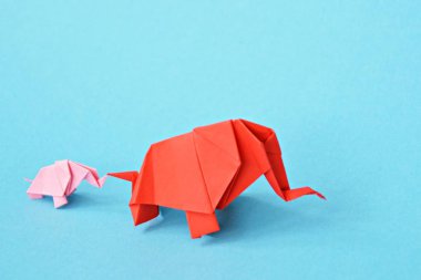 Mavi bir arka plan üzerinde pembe ve kırmızı stand iki kağıt katlanmış filler - küçük bir bebek fil ve origami tekniğine göre katlanmış bir anne fil ile kavram